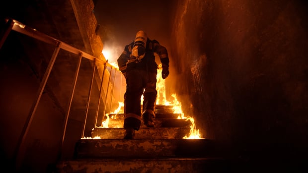firefighter going upstairs in a burning building